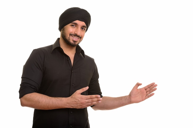Retrato de um jovem indiano feliz Sikh mostrando algo