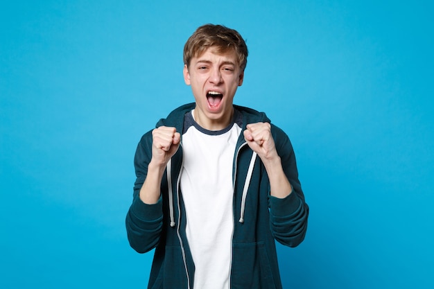 Retrato de um jovem infeliz em roupas casuais, gritando, cerrando os punhos isolados.