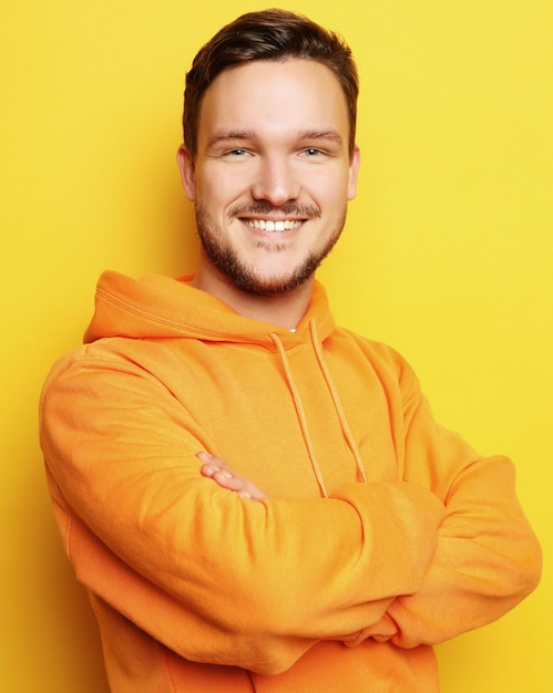 Retrato de um jovem inteligente em pé contra background amarelo