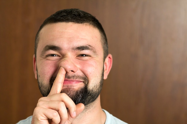 Retrato de um jovem inteligente moderno de cabelos pretos barbudo de óculos com corte de cabelo curto e gentis olhos negros, sorrindo no fundo desfocado. Conceito de juventude e confiança.