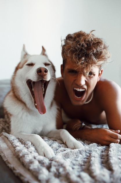 Retrato de um jovem irritado gritando enquanto estava deitado ao lado de um cão em casa