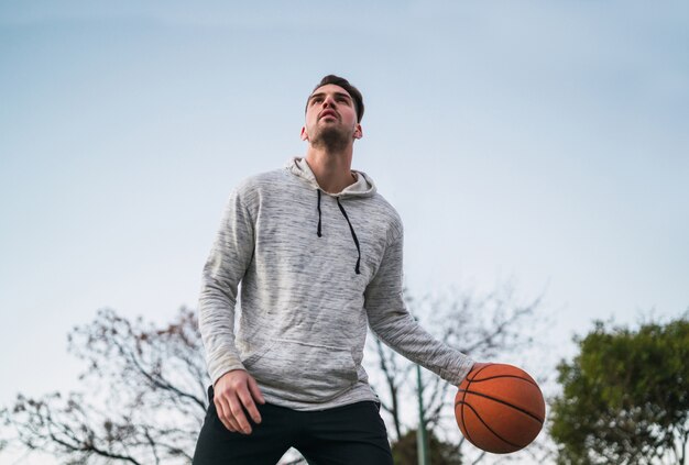 Retrato de um jovem jogador de basquete, jogando ao ar livre.