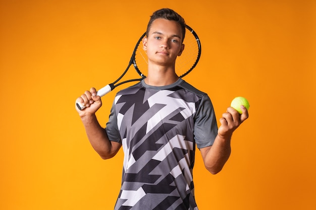 Retrato de um jovem jogador de tênis em fundo laranja close-up