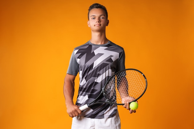 Retrato de um jovem jogador de tênis em fundo laranja