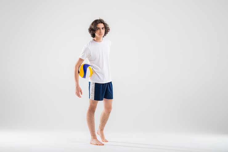 Foto retrato de um jovem jogador de vôlei com uma bola em um fundo branco