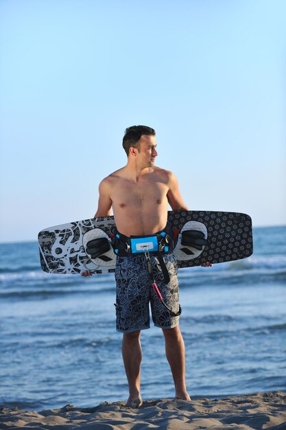 Retrato de um jovem kitsurf na praia ao pôr do sol