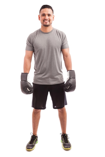 Retrato de um jovem latino com roupa desportiva e luvas de boxe prontas para praticar e sorrir