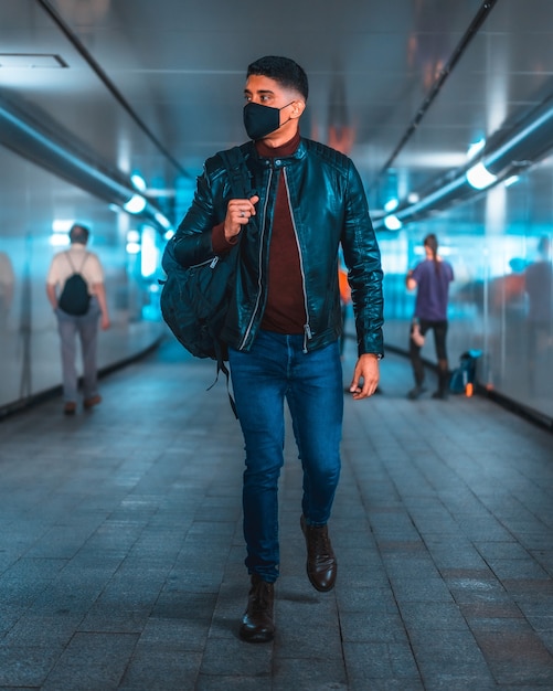 Foto retrato de um jovem latino no metrô da cidade. jeans, jaqueta de couro e sapatos marrons