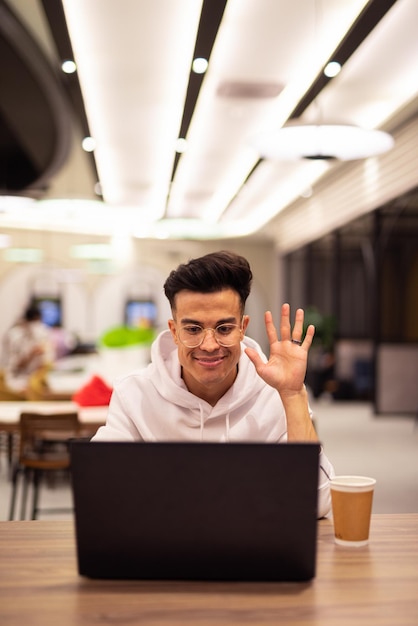 Retrato de um jovem legal bonito usando laptop no café