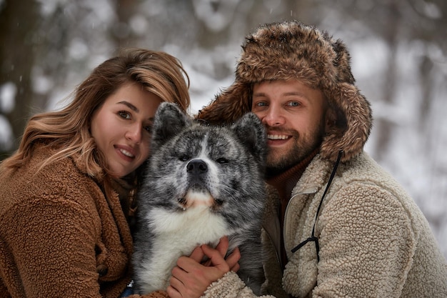 Retrato de um jovem lindo casal de aparência europeia com um cachorro husky na floresta de inverno