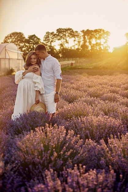 Retrato de um jovem lindo casal grávido em um campo de lavanda ao pôr do sol Conceito de família feliz