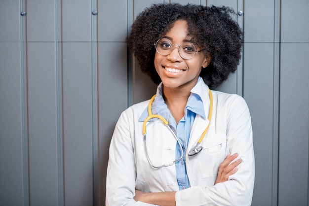 Retrato de um jovem médico africano de uniforme no fundo da parede cinza