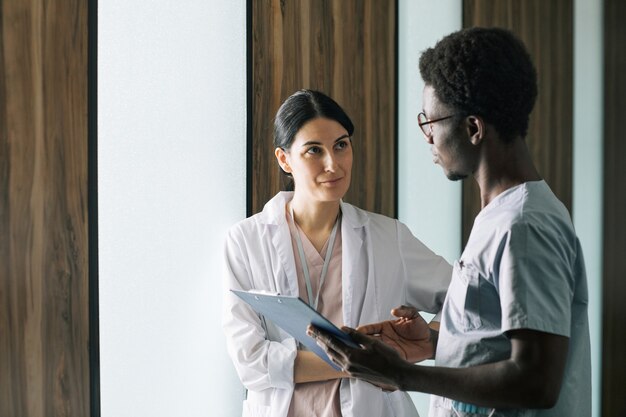 Retrato de um jovem médico afro-americano conversando com uma colega na clínica