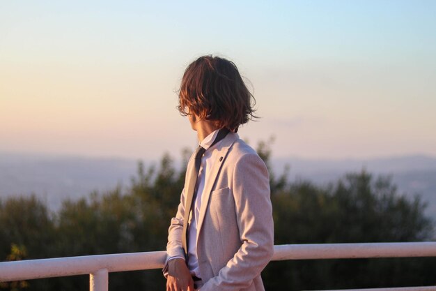 Retrato de um jovem menino de cabelos compridos em uma roupa elegante de terno blush, parecendo triste e com o coração partido