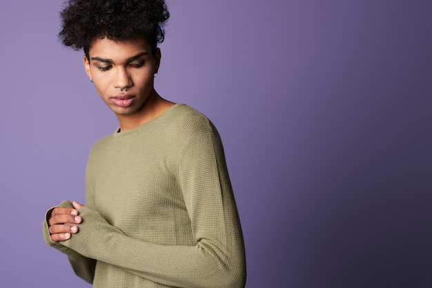 Retrato de um jovem moreno de pele escura em uma camiseta casual masculino hispânico em fundo roxo