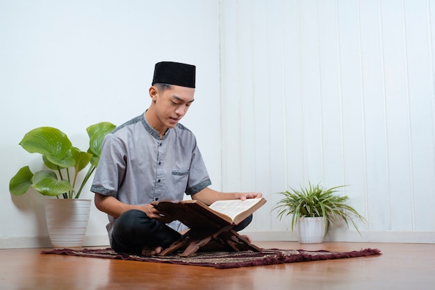 Retrato de um jovem muçulmano asiático lendo o sagrado alcorão no ramadan kareem em casa.