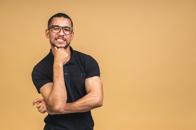 Retrato de um jovem negro afro-americano sorridente e alegre em pé isolado sobre fundo bege