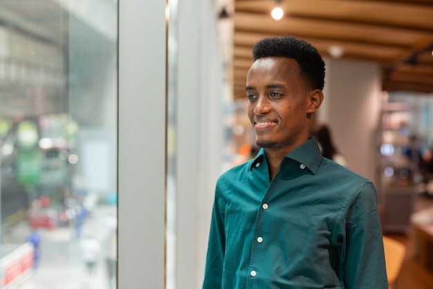 Retrato de um jovem negro bonito na cafeteria olhando pela janela