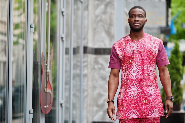 Retrato de um jovem negro vestindo roupas coloridas vermelhas tradicionais africanas.