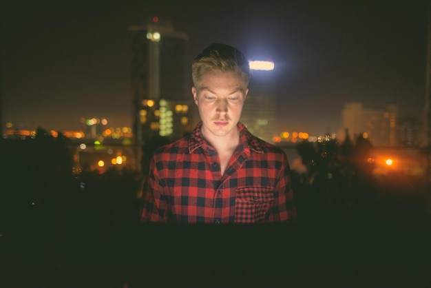 Foto retrato de um jovem olhando para uma cidade iluminada à noite