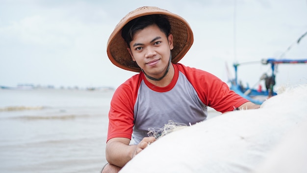 Retrato de um jovem pescador preparando uma rede de pesca na praia