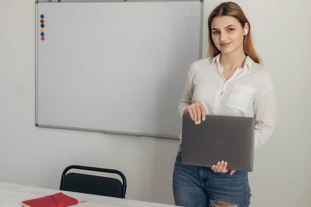 Retrato de um jovem professor na sala de aula Menina segurando um laptop Preparação para ensino à distância