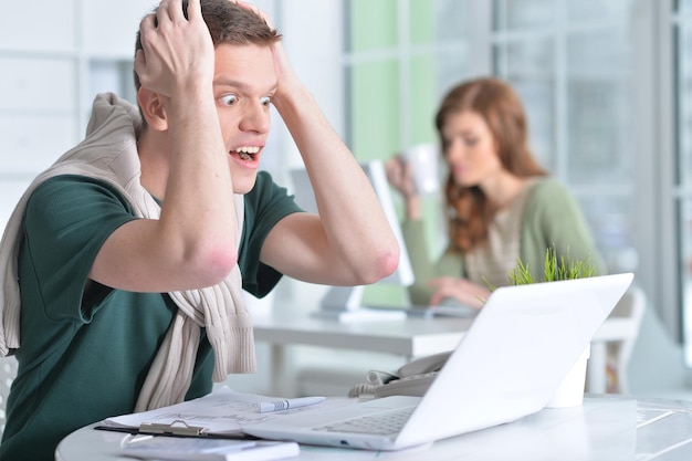 Retrato de um jovem que trabalha no escritório com um laptop