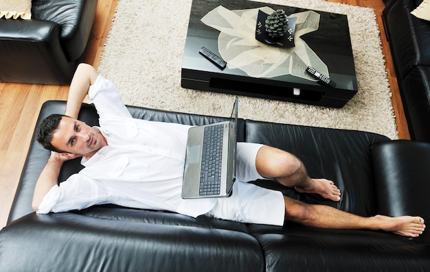 Retrato de um jovem relaxado usando laptop em casa interior