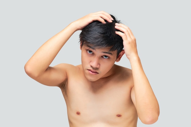 Foto retrato de um jovem sem camisa usando a mão na cabeça para verificar a saúde do cabelo