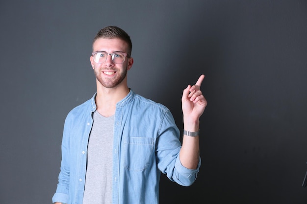 Retrato de um jovem sorridente apontando para cima