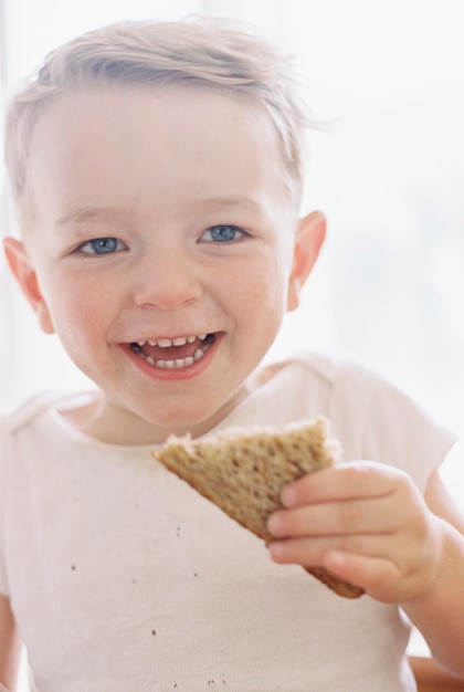 Retrato de um jovem sorridente comendo um sanduíche