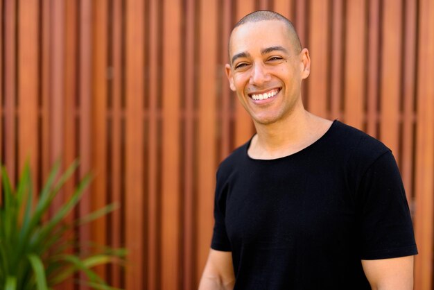 Foto retrato de um jovem sorridente de pé contra a parede