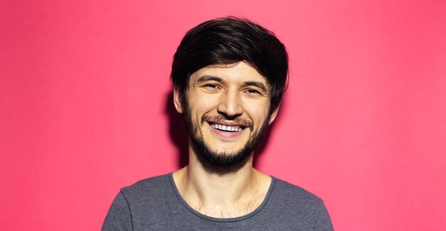 Retrato de um jovem sorridente isolado na superfície de um coral rosa