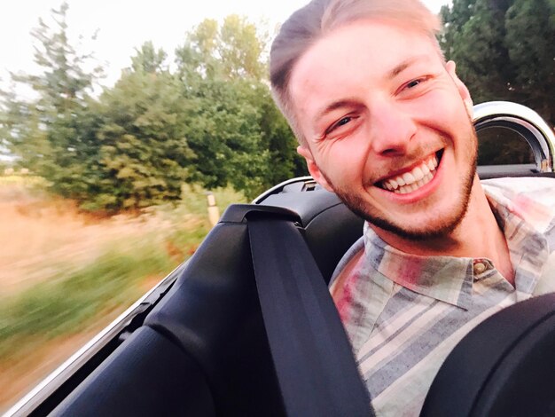 Foto retrato de um jovem sorridente no carro