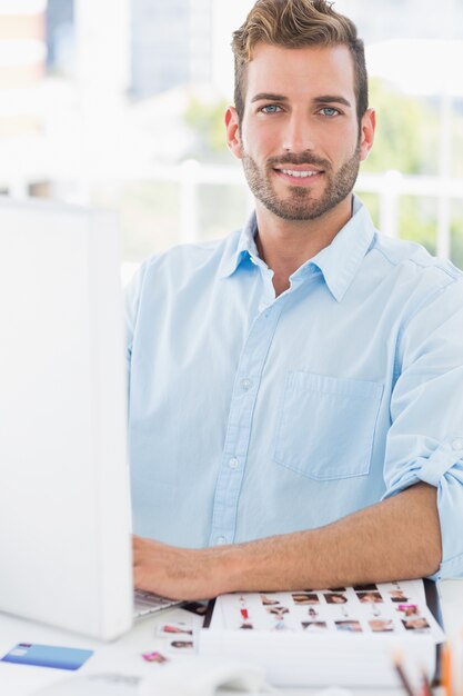 Foto retrato de um jovem sorridente usando o computador