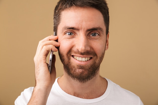 Retrato de um jovem sorridente, vestido de maneira casual, isolado, falando no celular