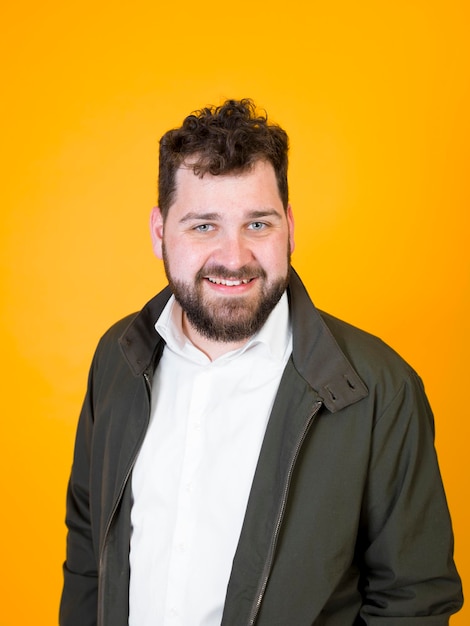 Retrato de um jovem sorrindo enquanto está de pé contra um fundo amarelo