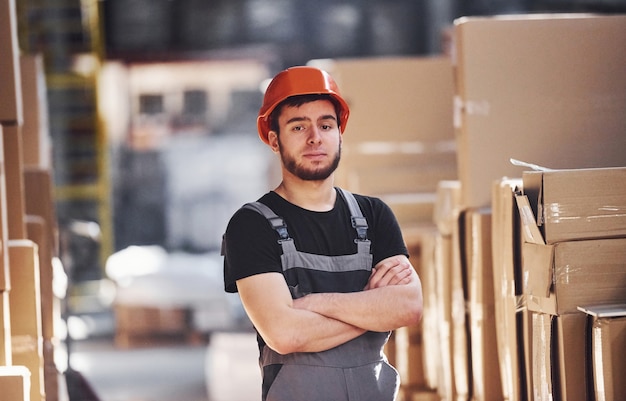 Retrato de um jovem trabalhador de armazenamento em armazém de uniforme e capacete.