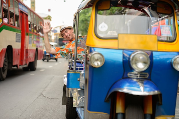 Retrato de um jovem turista bonito andando de tuk tuk como transporte público local na cidade de bangkok