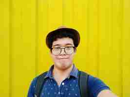 Foto retrato de um jovem usando óculos contra todo amarelo