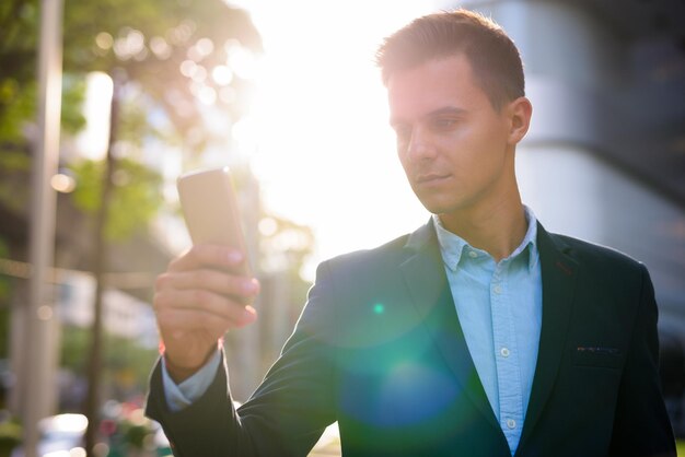 Foto retrato de um jovem usando um telefone celular ao ar livre