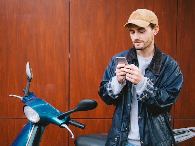 Retrato de um jovem usando um telefone móvel em uma scooter