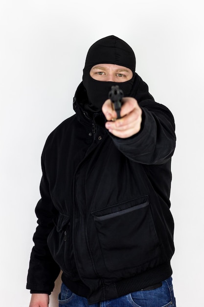 Foto retrato de um ladrão apontando uma arma enquanto está de pé em fundo branco