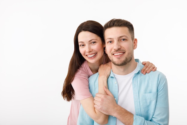 Retrato de um lindo casal amado Um cara e uma garota se abraçam e olham para a câmera sorrindo Em um fundo branco