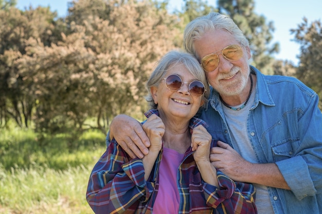 Retrato de um lindo casal de idosos desfrutando de uma excursão ao ar livre na floresta, com roupas casuais e óculos de sol