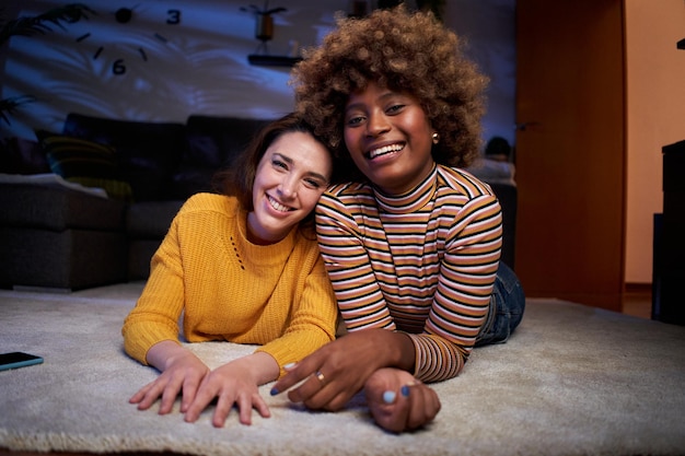 Retrato de um lindo casal lgbt de jovens lésbicas multirraciais posando sorrindo olhando para a câmera