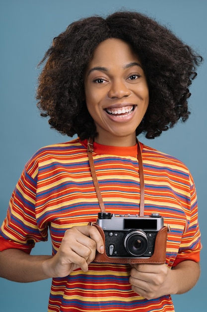 Retrato de um lindo fotógrafo afro-americano feliz segurando uma câmera retrô olhando para a câmera