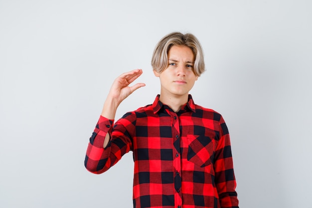 Retrato de um lindo menino adolescente mostrando um gesto bla-bla-bla com uma camisa quadriculada e com uma vista frontal sarcástica