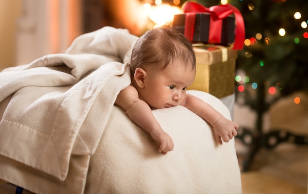 Retrato de um lindo menino deitado na cesta ao lado da árvore de Natal