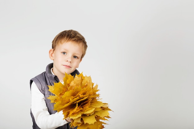 Retrato de um lindo menino feliz e alegre com folhagem de outono